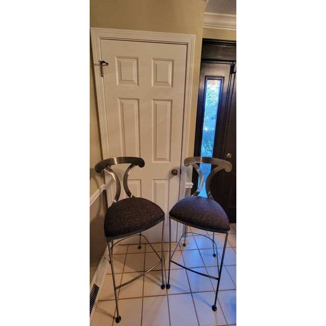 Beautiful pair of contemporary bar stools by Shaver Howard. Solid brushed steel metal frame with prominent sculptured...