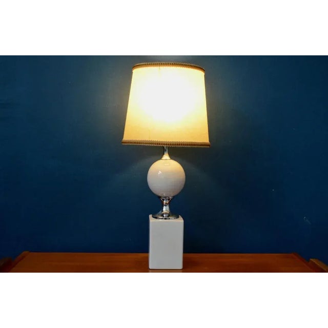 This pretty old table lamp is sober and elegant at the same time. Its base is made up of white enameled ceramic pieces,...