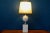 This pretty old table lamp is sober and elegant at the same time. Its base is made up of white enameled ceramic pieces,...