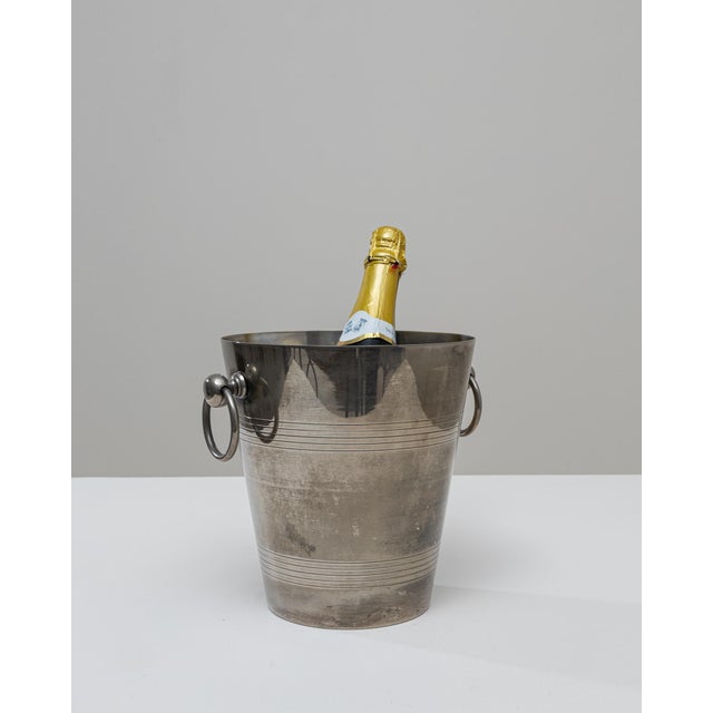 A 20th Century French silver-plated champagne bucket featuring a sleek, tapered silhouette and refined decorative banding....
