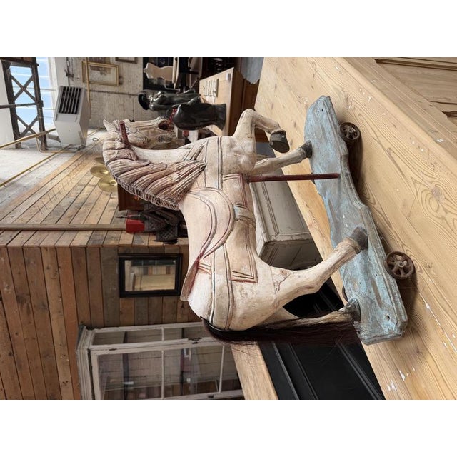 An antique wooden horse crafted in the style of carousel horses. It has retained its beautiful patina, and its base is...