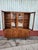 Vintage walnut china cabinet has a two-piece design with a glass-front upper hutch and a solid wood lower sideboard. The...