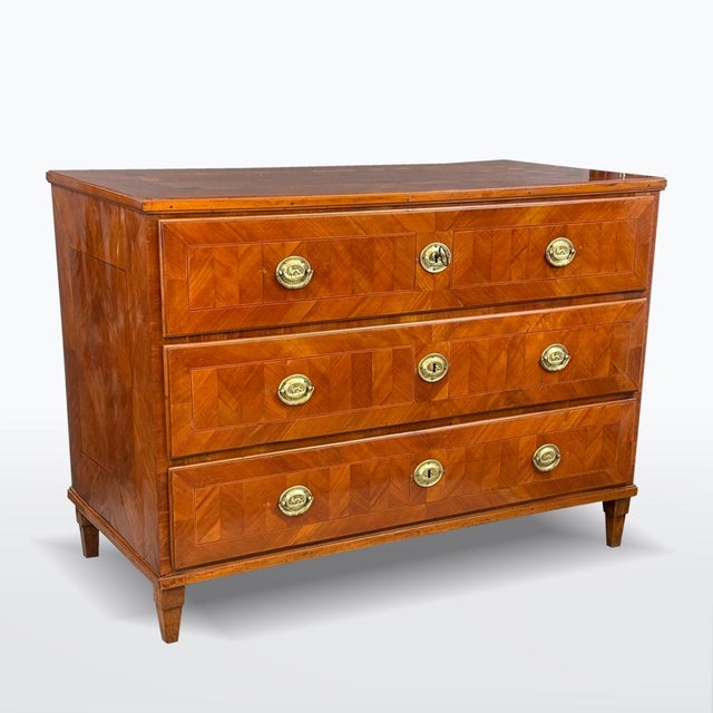 A three-drawer chest of drawers from the late Baroque period, made around 1800. The body is veneered with walnut,...