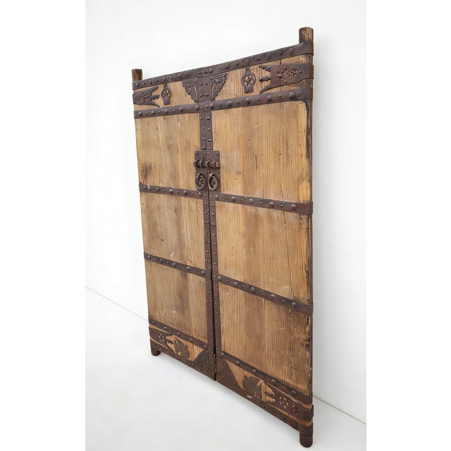 This pair of 19th century Chinese door panels showcase a masterful blend of rustic wood and hand-forged ironwork. Adorned...