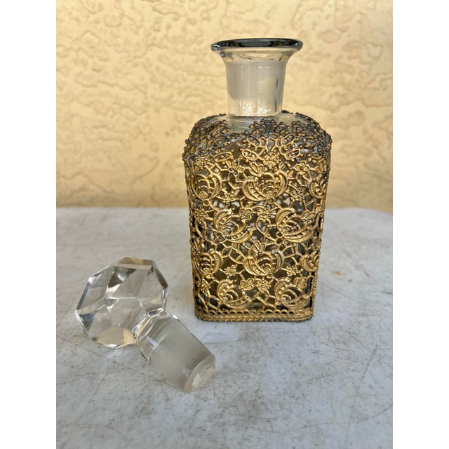 This is a vintage glass perfume bottle with gold-tone ormolu filigree overlay and a large faceted crystal stopper. Metal...