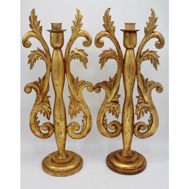A stunning pair of tall gold gilded wooden candlestick holders, made in Italy, circa 1920s. Lovely, ornate carvings of...