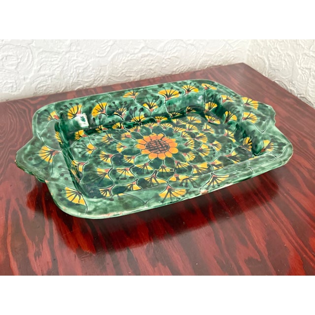 A hand-painted Mexican Talavera earthenware dish. It is deep and rectangular with tab handles on each end. The glaze is a...