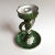 This ceramic candle holder is colored white and yellow with a green base. It features a daisy decoration in terracotta at...