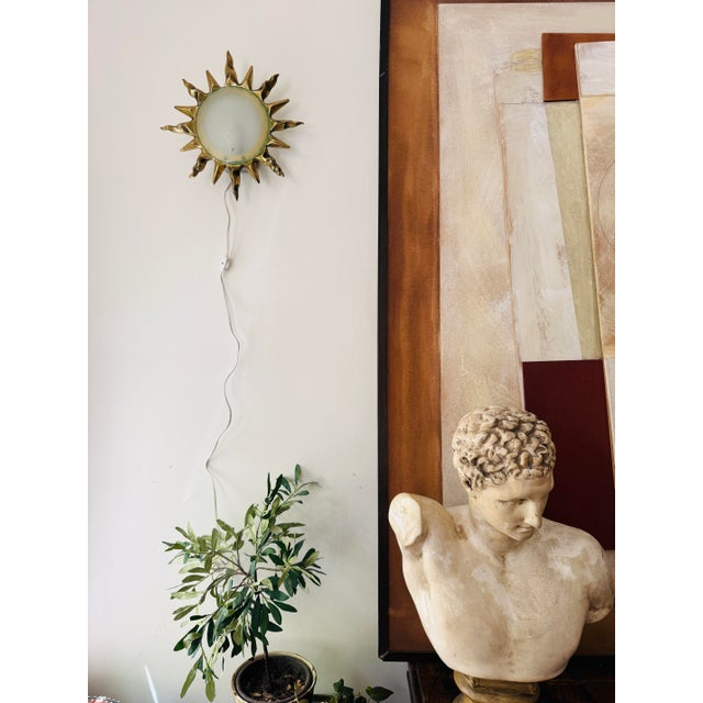 A striking pair of vintage sunburst wall sconces, cast in solid bronze with sculptural rays radiating around a softly...