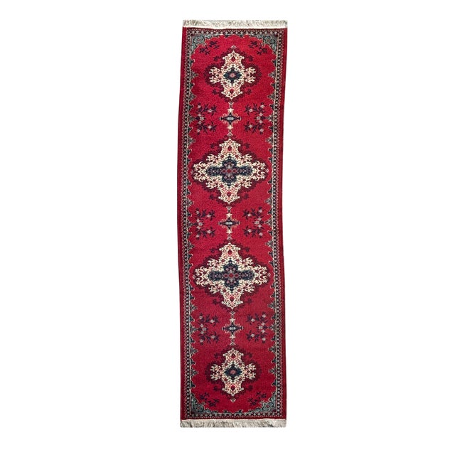 This vibrant red runner rug features a classic, ornate design characterized by a series of three large, symmetrical...