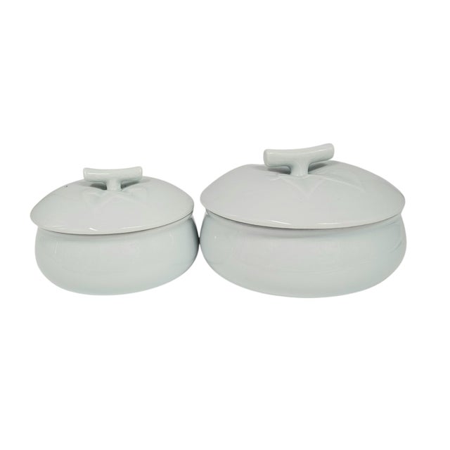 Two bowls, pale as morning frost, with lids shaped like fallen leaves. These celadon vessels feel plucked from a Korean...