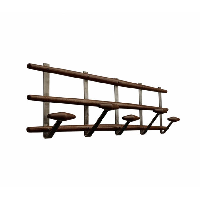 An elegant and functional wall-mounted coat rack that combines the warmth of turned wood with the industrial sleekness of...