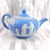 This is a light blue Wedgwood Jasperware teapot in an unknown pattern. The teapot has a white design of women and children...