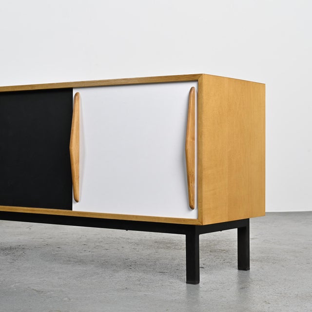 Cansado sideboard with an ash veneer body, opening with two sliding doors covered in black and white laminate and four...