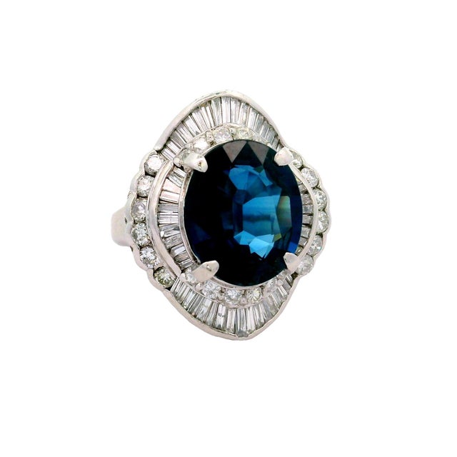 A striking cocktail ring featuring an exquisite 8.53-carat oval-shape blue sapphire. The deep blue of the sapphire is...