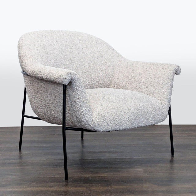 This lounge chair by Four Hands features a soft white bouclé fabric and slim black metal legs. The curved back and...