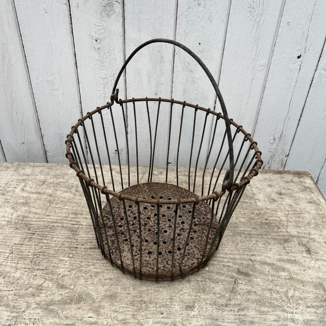 This vintage wire egg basket features a perforated bottom with a charming rusted patina, offering both utility and rustic...