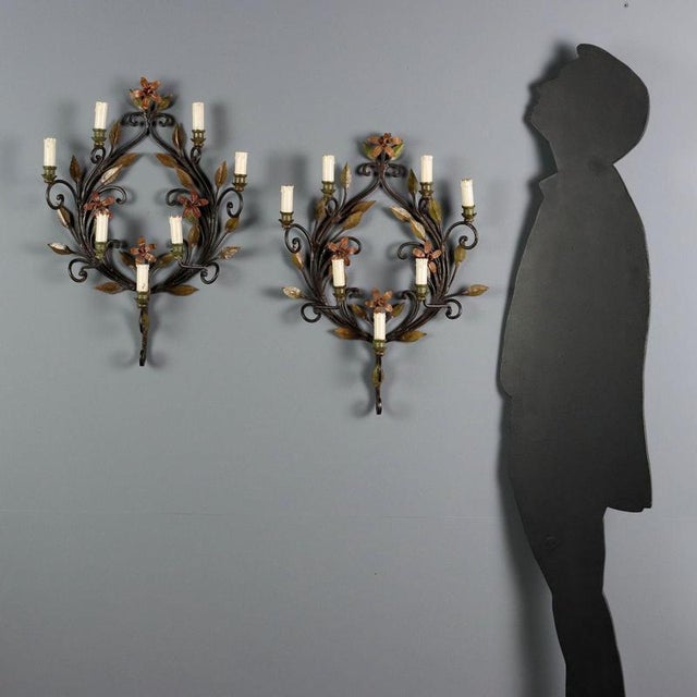 Pair of painted iron and sheet metal wall sconces. Six lights supported by curved arms, part of a floral and leafy wreath...