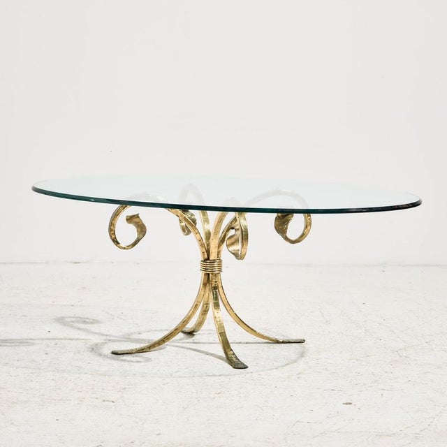 Brass coffee table from the 1970s. The table has an organic-shaped base and a hardened glass top. with some surface...