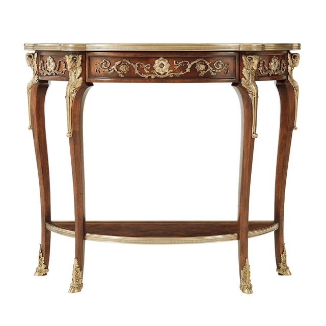 A French-style console table applied with very fine brass mounts, the brass bound top with a frieze drawer, on ram's head...