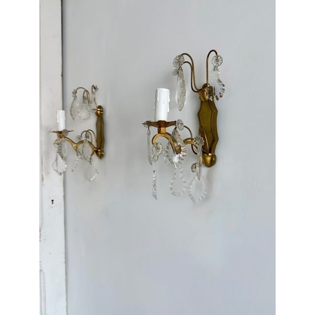 Elegant pair of French vintage wall sconces dating from the 1940s, crafted from shaped brass and decorated with clear...