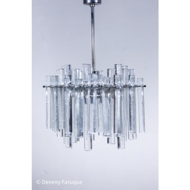 Art glass chandelier with iced textured cast glass rods of various lengths. The frame is in its original chrome finish....