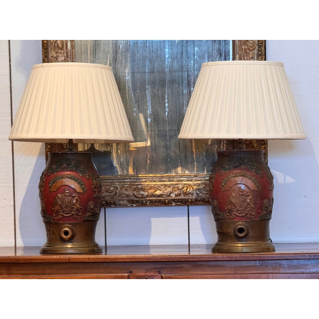 A pair of lamps formed from whisky casks, each with a rounded barrel form and raised relief decoration depicting heraldic...