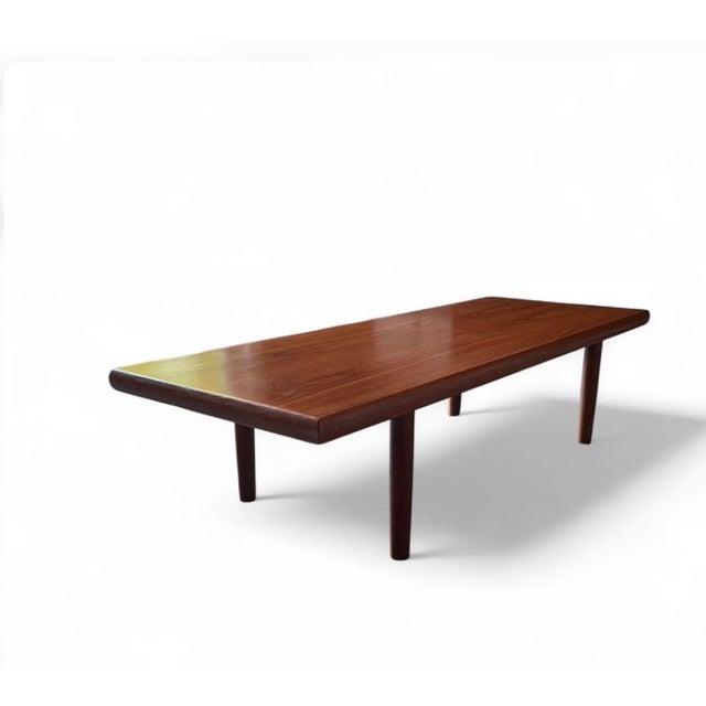 Beautiful teak coffee table with a warm tone and a striking natural grain across the top. It’s long and low (58” L x 21” W...