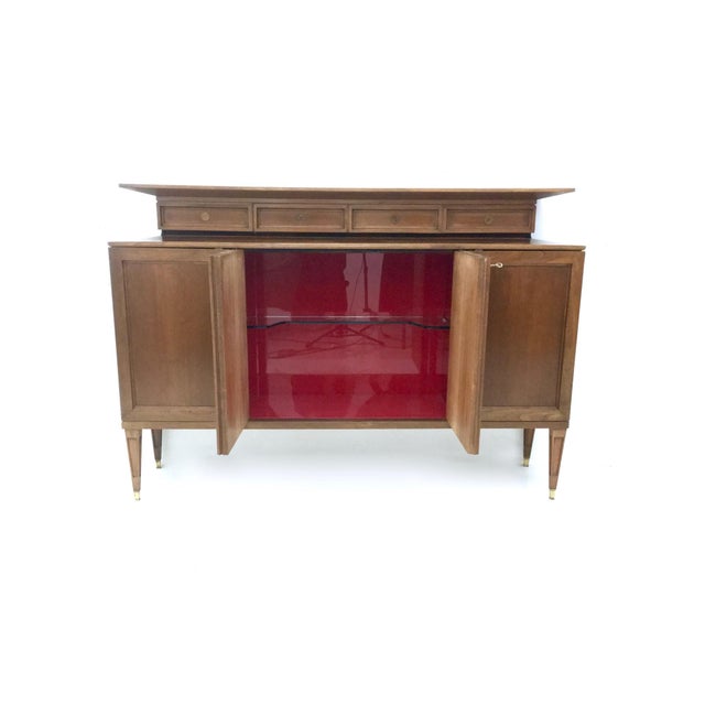 Made in Italy, 1950s. This cabinet is made in walnut and features brass details, walnut interiors and glass shelves. It is...