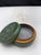 Handmade earthenware lidded box featuring a green glaze with abstract decorative patterns on the lid. The interior is...