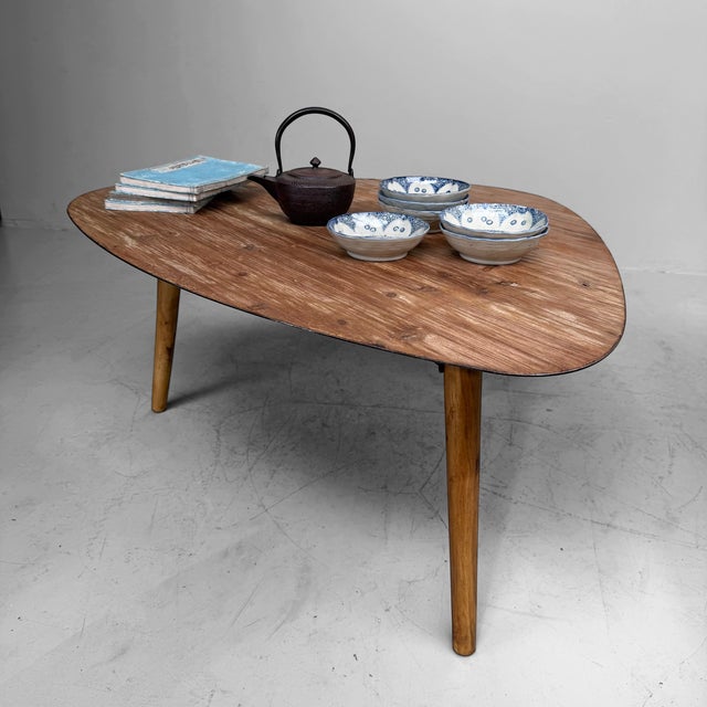 Vintage wooden coffee table, probably originating from Belgium. The table features an organically shaped top with soft,...
