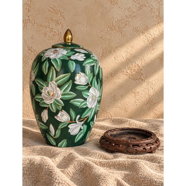 A striking vintage chinoiserie ginger jar featuring a rich emerald-green ground, beautifully detailed white floral and...