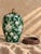 A striking vintage chinoiserie ginger jar featuring a rich emerald-green ground, beautifully detailed white floral and...