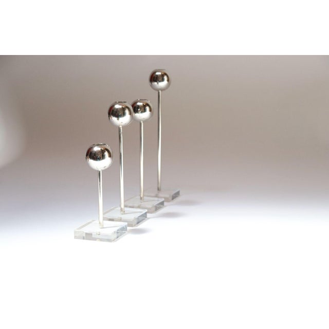Set of four Mid-Century candlesticks (ca. 1970s, USA). Composed of chrome orb-form bulbs supported by cylindrical lucite...