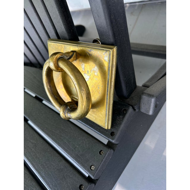 This vintage solid brass door knocker features a substantial round ring mounted on a square brass backplate with raised...