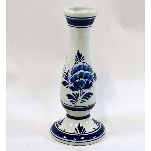 A classic Delft bulb vase with an elongated neck opening up to a flared rim, resting on a bulbous body and a ringed...