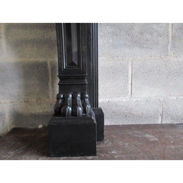 A 19th century (dated 1813) french black napoleon marble fireplace with panelled freeze and corner blocks on scrolled legs...