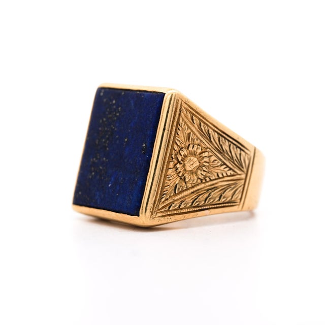 Natural lapis lazuli square tablet is bezel-set in an 18K yellow gold men's signet ring featuring deeply hand-engraved...