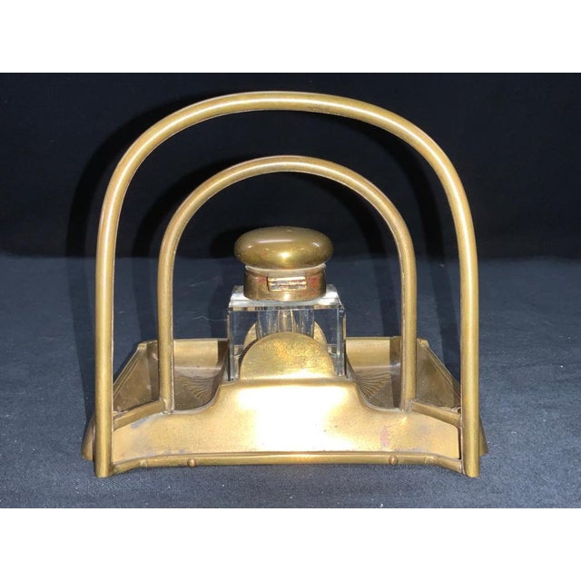 A vintage brass desk top square crystal inkwell with a domed hinged top on a rectangular tray-style base with two arched...