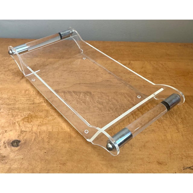 This vintage Lucite and chrome serving tray embodies the sleek sophistication of mid-century modern design, where...