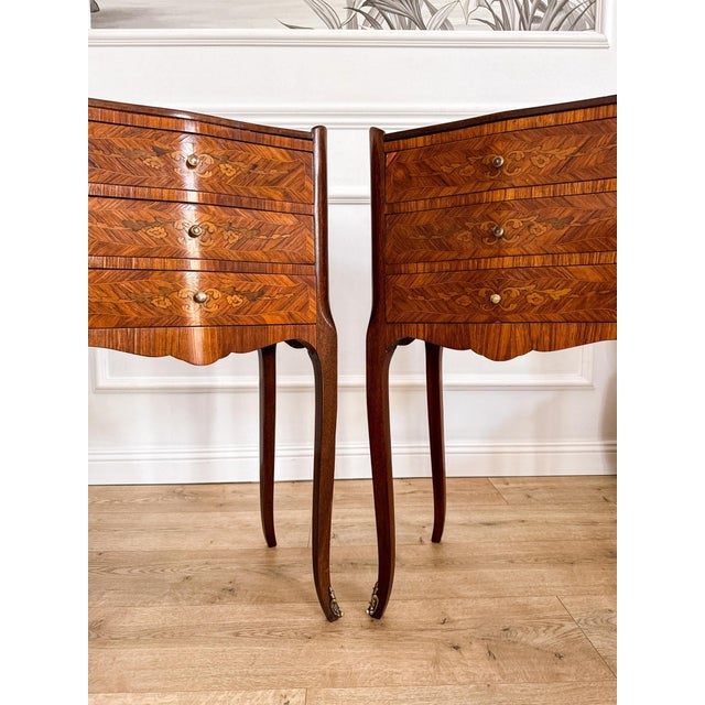 A pair of elegant french bedside tables in the louis xv style, made in the mid-20th century. Each has three serpentine...