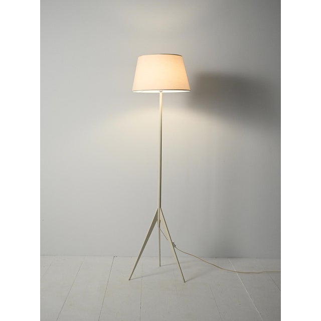 Scandinavian floor lamp from the 1950s/1960s in white-painted wood, featuring a slender tripod structure and a lampshade...
