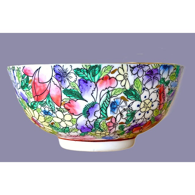A vibrant, hand‑painted porcelain Chinese bowl covered in flowers - pinks, purples, blues, and sunny yellow tones. The...