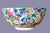 A vibrant, hand‑painted porcelain Chinese bowl covered in flowers - pinks, purples, blues, and sunny yellow tones. The...