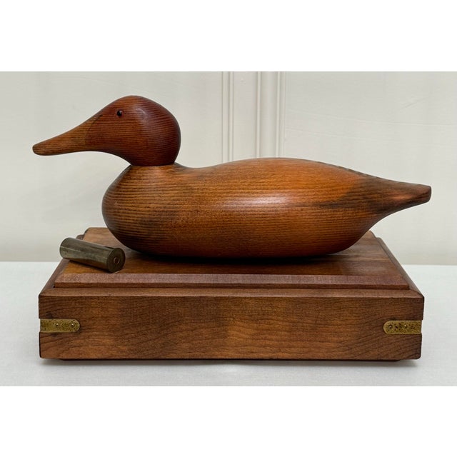 Various woods with exquisite grain throughout are consistent in this solid wood lidded wood box topped with a duck decoy....
