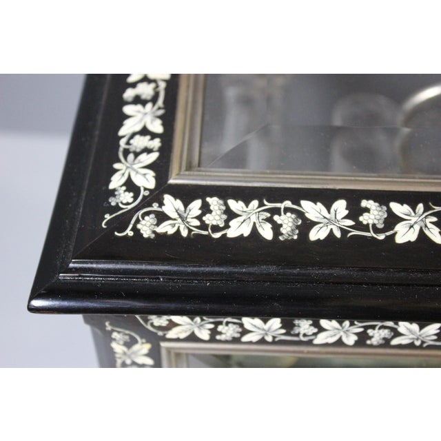 A Napoleon III period liquor cabinet in blackened wood with marquetry of leaves and bunches of grapes, comprising four...