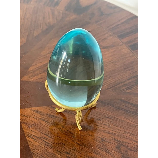 Vintage blue glass polished egg on gold brass tripod stand.