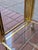 Vintage two-tier bar cart with a tubular brass frame, wide curved brass corner panels, and two clear glass shelves, on...