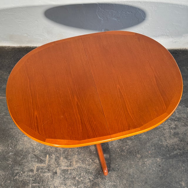 This oval extendable dining table is a refined example of British mid-century teak furniture from the 1960s, featuring an...