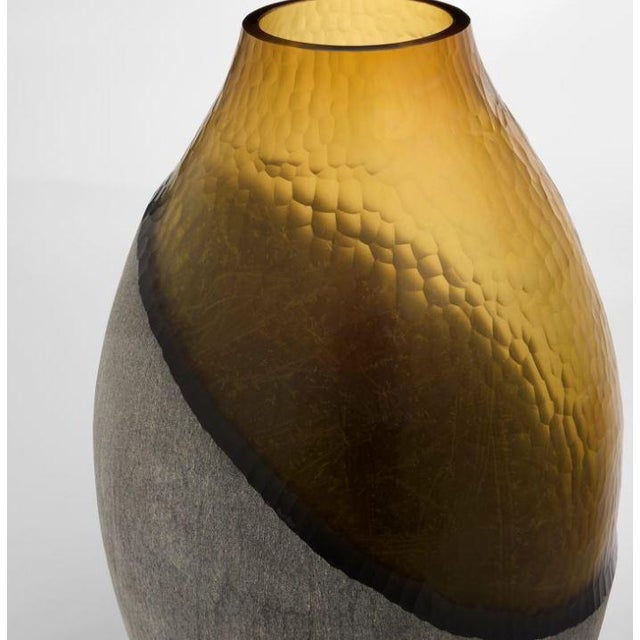 The Geode Vases contrast shimmering gold iridescence with sandblasted black cased glass, creating a dynamic interplay of...